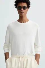 Jersey color topo de corte amplio, tejido en hilatura con mezcla de viscosa. Tiene cuello redondo, manga larga y terminaciones en rib.