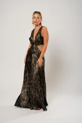 Vestido largo de fiesta con estampado abstracto en tonos dorados y negros. Tiene escote en V, corte en la cintura y aberturas laterales.