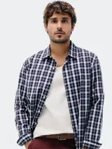 Camisa de manga larga con estampado a cuadros vichy en tonos azul marino y blanco. Presenta cuello camisero y botones frontales.