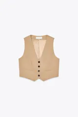 Chaleco color beige de corte cropped, con escote en V, sin mangas, bolsillos frontales y cierre con cuatro botones.