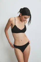 Conjunto de ropa interior negro con corpiño tipo bralette de encaje y colaless de encaje.