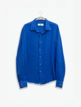 Camisa celeste de lino, de manga larga con botones de coco y parche de la marca.