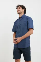 Camisa de manga corta azul con estampado de lunares blancos, cuello button-down y bolsillo en el pecho.