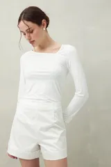 Top blanco de manga larga con escote asimétrico.