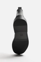 Bota Chelsea marrón de cuero, con elásticos laterales y tirador trasero. Suela negra con ligero tacón.
