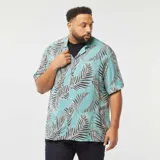 Camisa celeste con estampado de hojas de palmera en tonos negro y blanco, de corte holgado y manga corta.