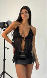 Top halter negro de encaje transparente con volados en los bordes y ajuste frontal con lazo.