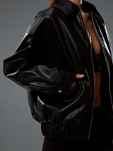 Chaqueta bomber negra de cuero sintético con cierre frontal y cuello clásico.