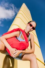 Bolso deportivo tipo bolsa de nylon color rojo brillante, con cordón ajustable en la parte superior que funciona como cierre. Presenta un pequeño logo rectangular blanco y negro en el frente.