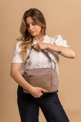 Bandolera de diseño moderno, color beige rosado, con correa regulable y bolsillo frontal con cierre.