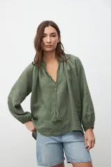 Camisa verde militar de crepe con escote en V, mangas largas abullonadas y detalle de cordón con borlas en el escote.