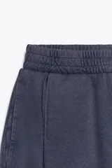 Pantalón color arena de tiro medio con cintura elástica, bolsillos laterales ocultos y pinzas en el delantero.