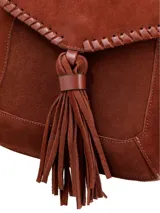 Bandolera de cuero gamuza color chocolate, con correa larga regulable, solapa con detalle de pespuntes y borla decorativa.