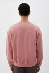 Buzo rosa de tejido liviano de mezcla de algodón con interior cepillado suave, cuello redondo ribeteado, hombros caídos y remate ancho acanalado en puños y bajo. Corte holgado.