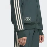 Campera Adidas de la Juventus, color verde oscuro con rayas blancas en las mangas. Tiene cierre frontal, cuello alto, bolsillos laterales y escudo de la Juventus bordado en el pecho.