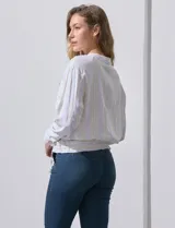 Chaqueta de lino a rayas verticales amarillas y celestes, con cuello a la base, abertura central con botones, bolsillos delanteros y ruedo con jareta de ajuste.