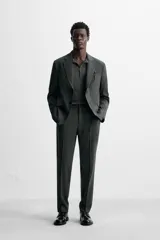 Pantalón de vestir azul marino, de corte slim fit, con bolsillos laterales y traseros. Se ajusta a la cintura con cinturón de cuero marrón.
