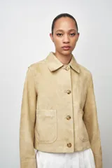 Chaqueta de mujer realizada en piel de ante color beige. Tiene cuello solapa, manga larga, bolsillos de plastrón en delantero y cierre frontal con botones.
