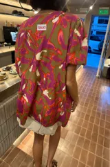 Blusa de calce holgado con estampado floral en tonos marrones, fucsias, naranjas y blancos. Escote en V con doble lazo ajustable y mangas 3/4 con volumen.