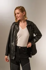 Chaqueta negra de eco-cuero con cuello camisero, corte holgado, cierre con broches y tachas plateadas.