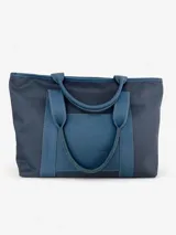 Bolso tote azul con paneles laterales en lona y panel central en cuero texturizado. Tiene doble asa corta de cuero y bolsillo frontal.