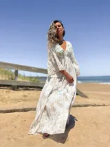 Vestido largo color crudo con estampado dorado, escote en V y mangas acampanadas.