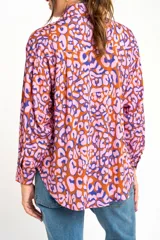 Camisa de viscosa color naranja con estampado animal print en tonos rosa y azul. Corte oversize, cuello clásico y cierre frontal con botones.