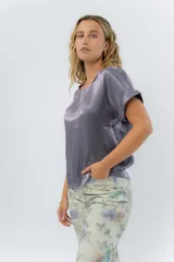 Blusa gris lavanda metálico de corte recto y fluido, con mangas cortas con vuelta, escote redondo y abertura en la espalda.