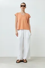 Remera color durazno con cuello en V y detalle de trenza en el escote.