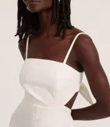 Mono largo color blanco, de breteles finos y escote recto. Presenta recorte cut-out en la cintura y lazo en la espalda.