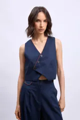 Chaleco color crudo con cuello en V y botones frontales.