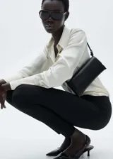 Pantalón negro de tejido de punto ligero, corte slim fit, cintura elástica, detalle de costuras verticales y cierre con cremallera en los bajos.