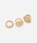 Set de tres anillos dorados de metal con diferentes diseños: uno liso y ancho, otro con una forma ovalada y otro con esferas.