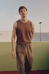 Pantalón marrón claro de lino y algodón, corte recto, con cintura elástica ajustable con cordón, bolsillos laterales y trasero.