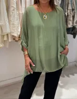 Blusa verde oliva de seda italiana, con cuello a la base y corte asimétrico. Incluye musculosa integrada.