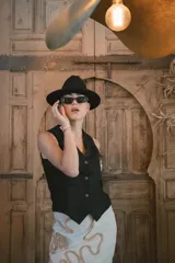 Chaleco negro de vestir, con escote en V y cierre frontal de botones dorados.