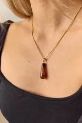 Collar dorado con cadena fina y dije colgante en forma de lágrima de piedra natural azul con vetas blancas.