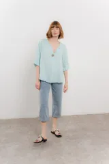Blusa celeste de lino, con escote en V, manga tres cuartos y botón de madera.