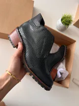 Botas cortas de cuero negro con textura de cocodrilo, taco de madera y suela de goma. Hechas en Uruguay.