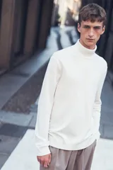 Polera blanca de punto fino, con cuello alto, mangas largas y corte ajustado.