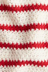 Cárdigan corto de punto texturizado a rayas rojas y blancas, con cuello redondo, cierre frontal con botones dorados y bolsillos decorativos con botón. Remate acanalado en cuello, tapeta, puños y bajo.