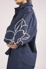 Camisa azul marino con bordados de flores blancas en mangas y ruedo.