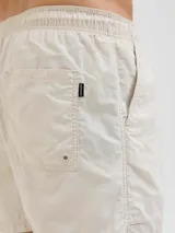 Short de baño color beige con cintura elástica ajustable con cordón, bolsillos laterales y logo de Originals Studio estampado en la pierna.