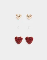 Set de tres pares de aros pasantes: un par de perlas, un par de corazones dorados y un par de corazones rojos con glitter.