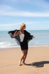 Capa tejida color negro, con flecos largos en los bordes.