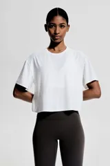 Remera deportiva blanca de corte boxy, confeccionada en tejido funcional DryMove™ que ayuda a absorber el sudor. Tiene cuello redondo, mangas cortas con hombros caídos y bajo recto.