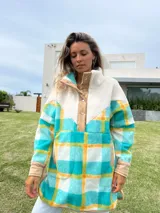 Buzo largo con cuello alto de polar color crema y cuerpo con estampado de cuadros en tonos celeste, amarillo y blanco.