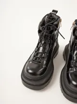 Bota negra de cuero con suela de goma, diseñada para un estilo urbano y práctico, con cierre lateral para facilitar el calzado.