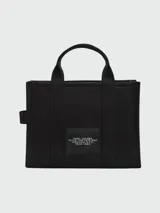 Bolso tote mediano color beige con estampado frontal del logo "The Tote Bag Marc Jacobs" en blanco. Tiene doble asa corta y correa larga extraíble de tela azul marino.