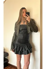 Vestido strapless de cuero ovino color negro, con volados y detalles de pequeñas piedras brillantes.